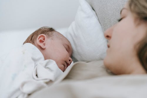 Mother sleeping with newborn baby in bedroom