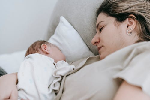 Mother with baby sleeping on bed