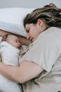 Mother with newborn baby sleeping on bed