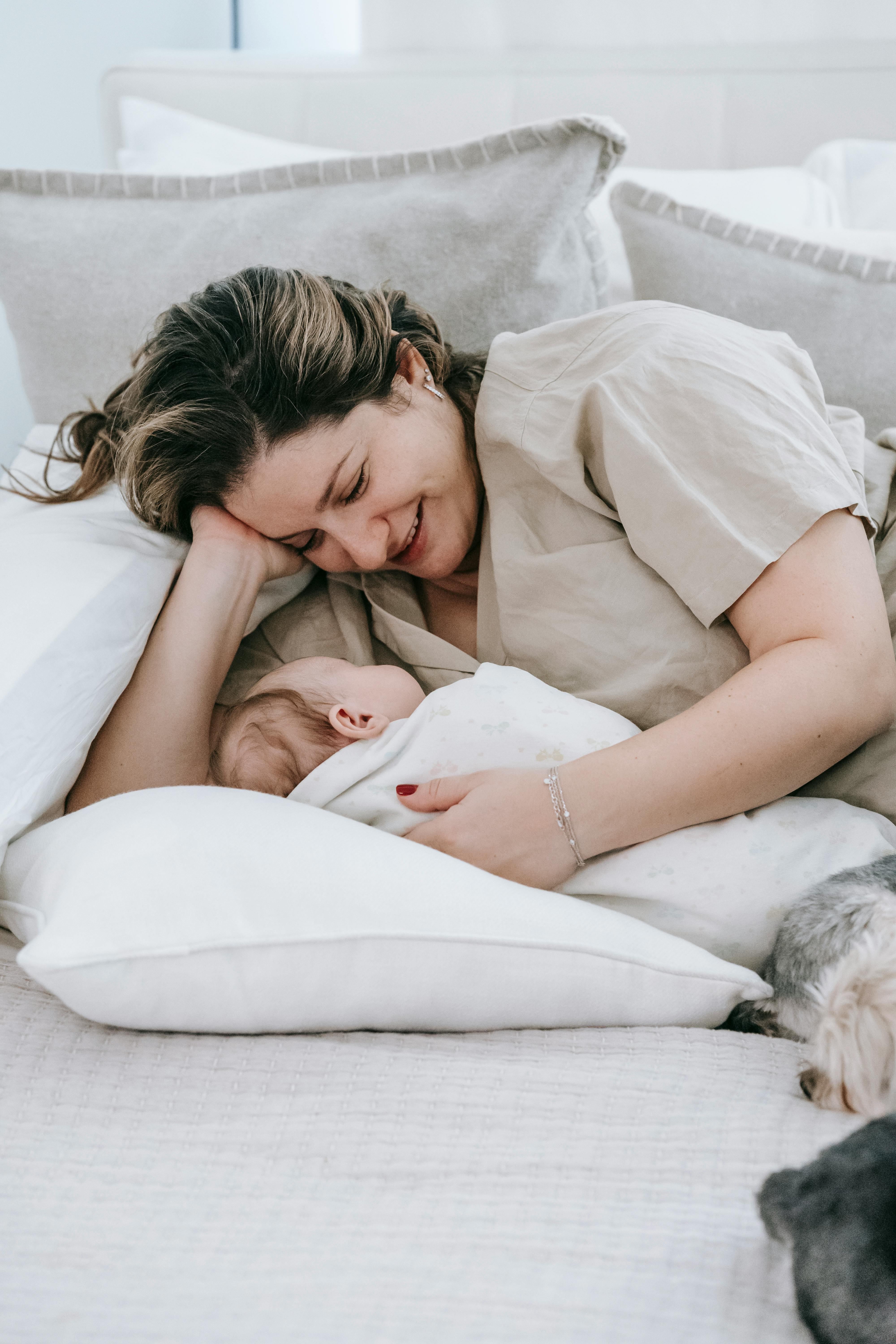 cheerful woman with infant baby in bed