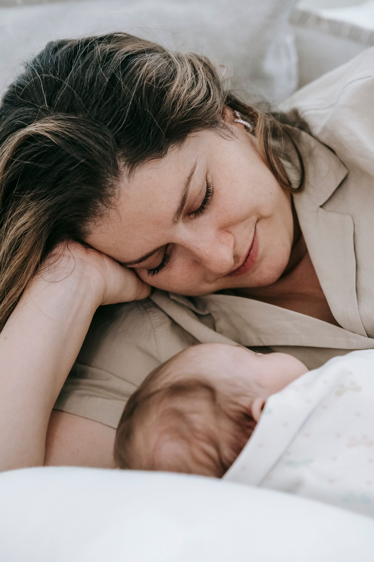 Smiling mother cuddling her newborn in a bright bedroom