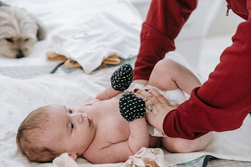 Faceless mother changing diaper for newborn baby