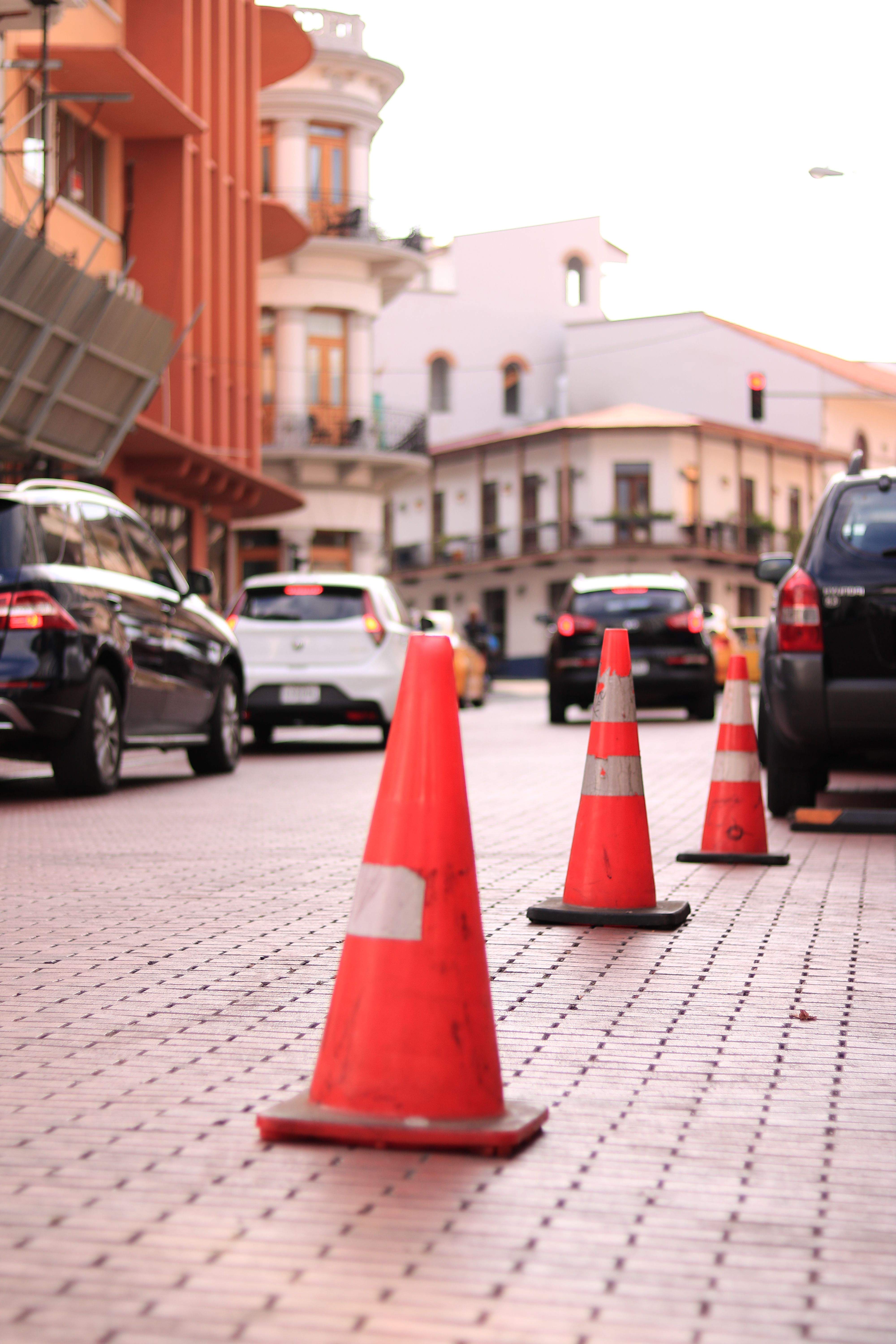 Traffic cones line a cobblestone street in bustling Panama City, capturing urban life.