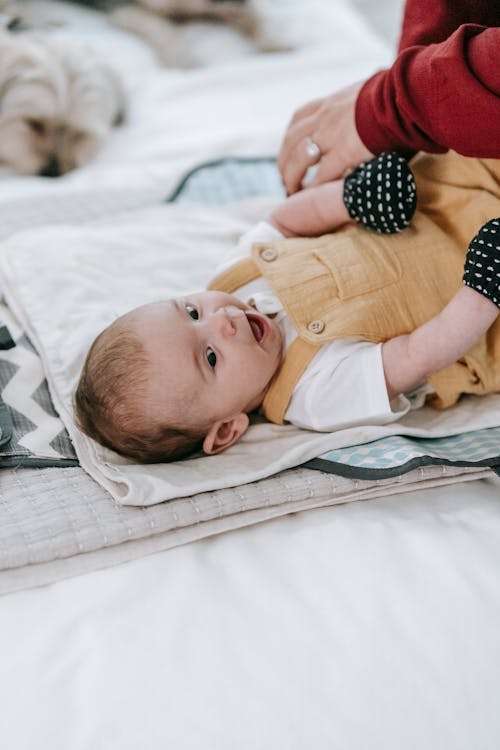 Faceless woman dressing baby on couch