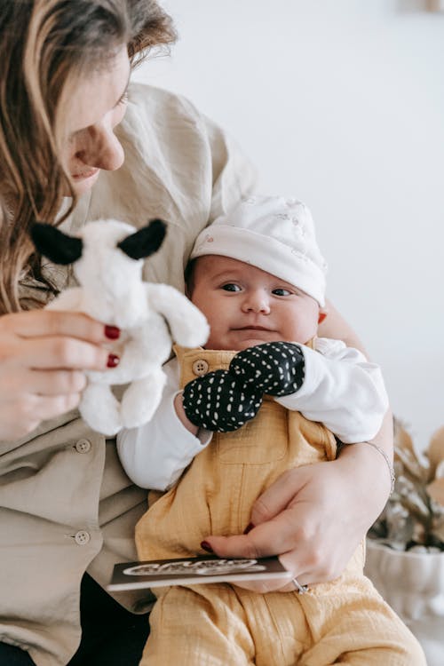 Faceless mother showing toy to newborn baby · Free Stock Photo