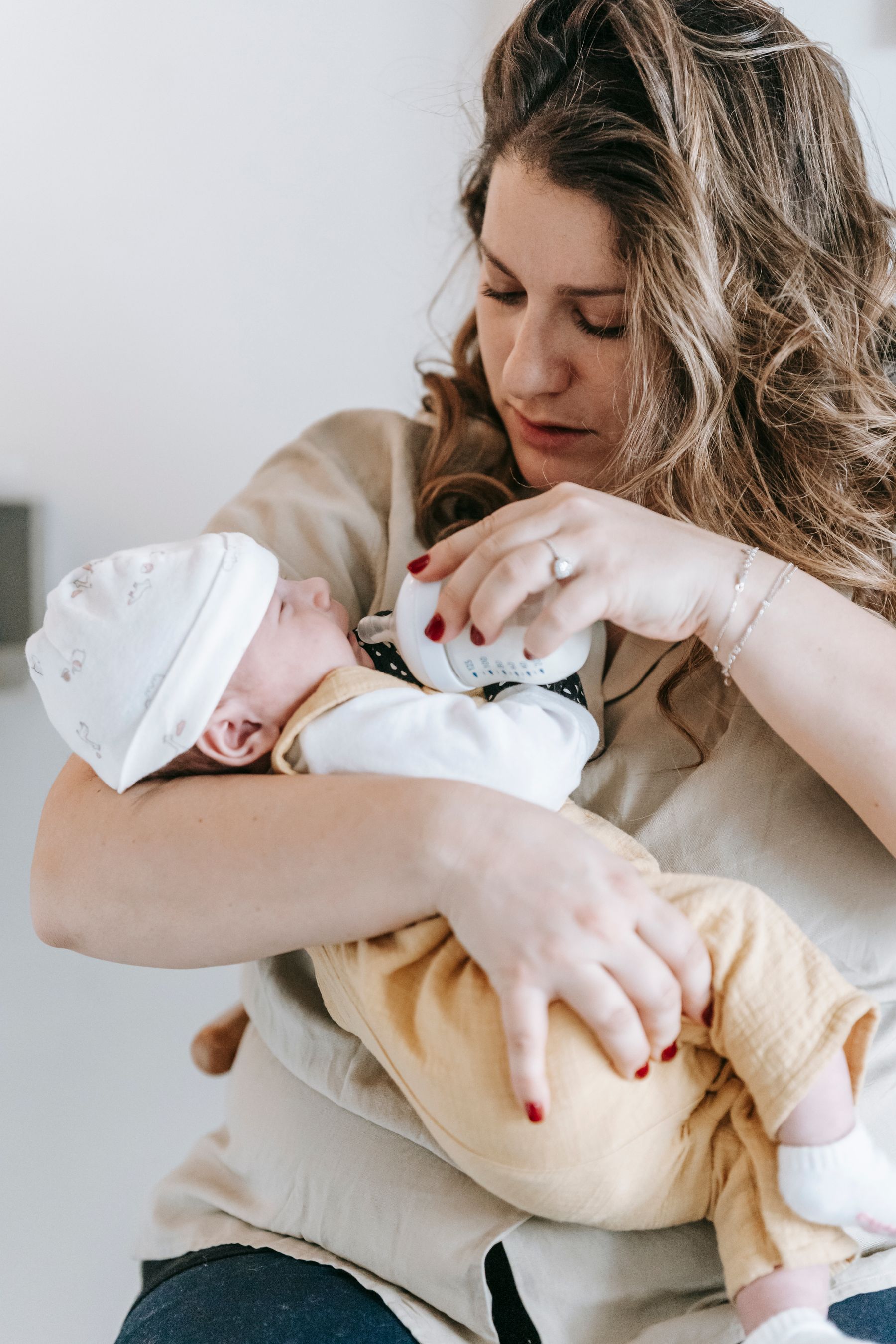 Mother gently bottle feeding her baby in a calm home setting