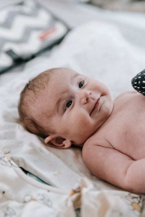 Free Charming baby lying on a patterned blanket indoors, showcasing a serene moment. Stock Photo