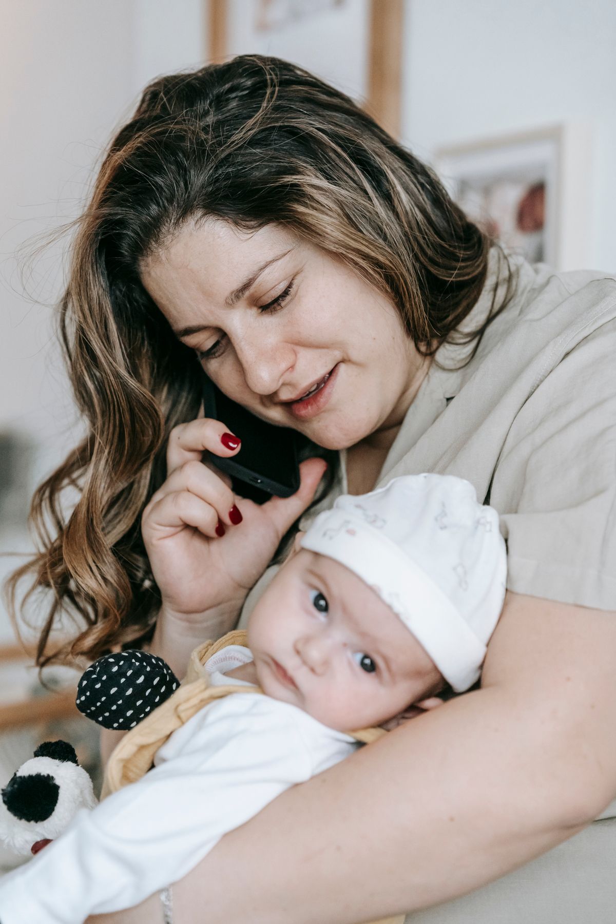 Mother holding her infant while speaking on a smartphone