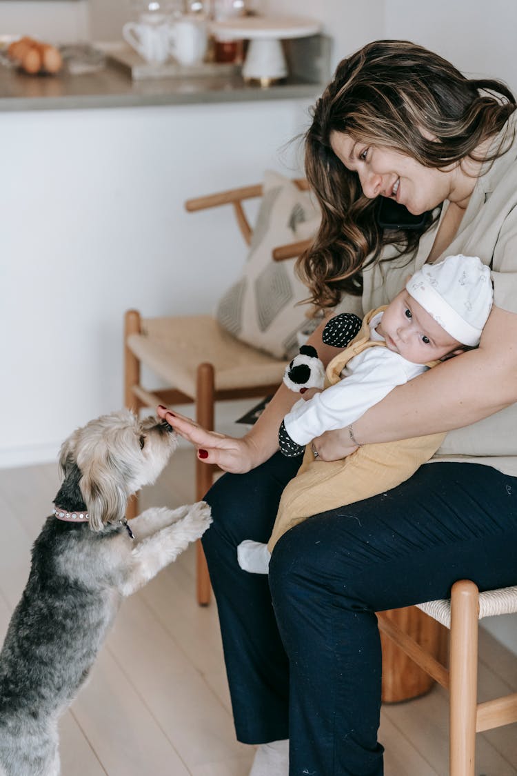 Cheerful Woman With Infant Baby Playing With Dog