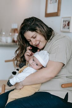 A mother lovingly holds her baby while speaking on the phone at home.