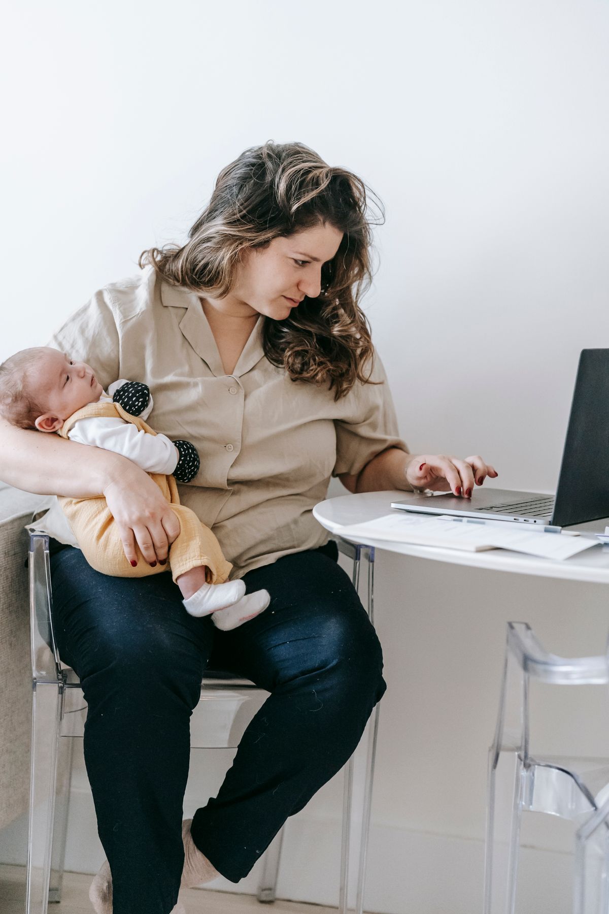 Mother holding baby while using laptop at home