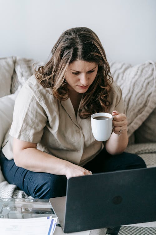 Female freelancer with laptop and cup of hot drink