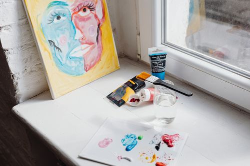 Free A bright, minimalistic workspace featuring abstract art and painting tools by a window. Stock Photo