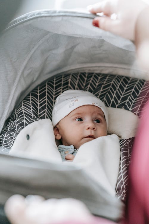 Baby in carriage looking at mom who is cropped out of image