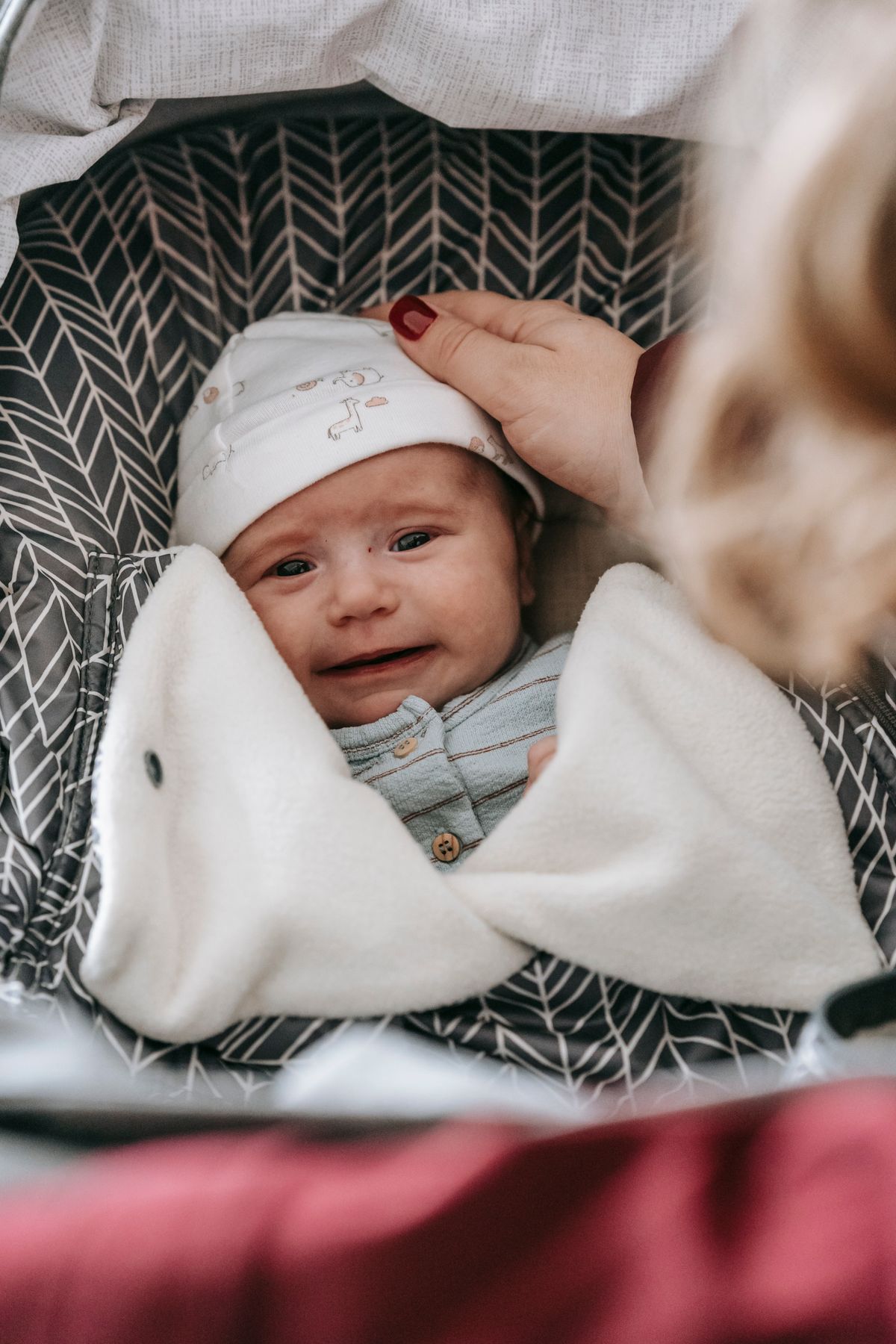 A mother leaning over a pram to soothe her crying newborn
