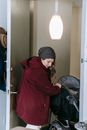Woman with baby carriage leaving apartment