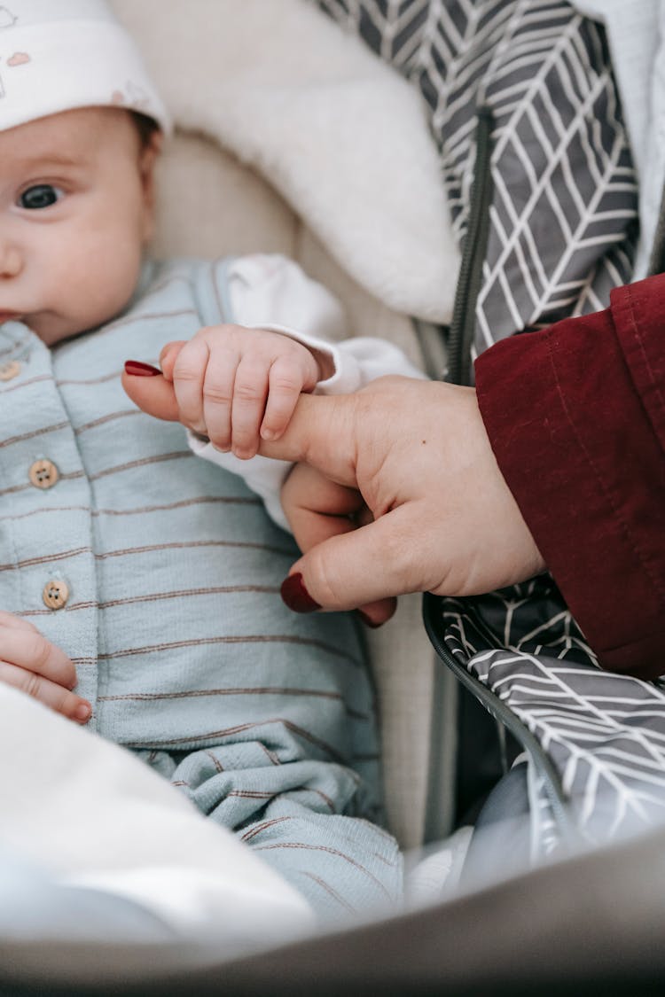 Newborn Lying In Crib And Holding Hand