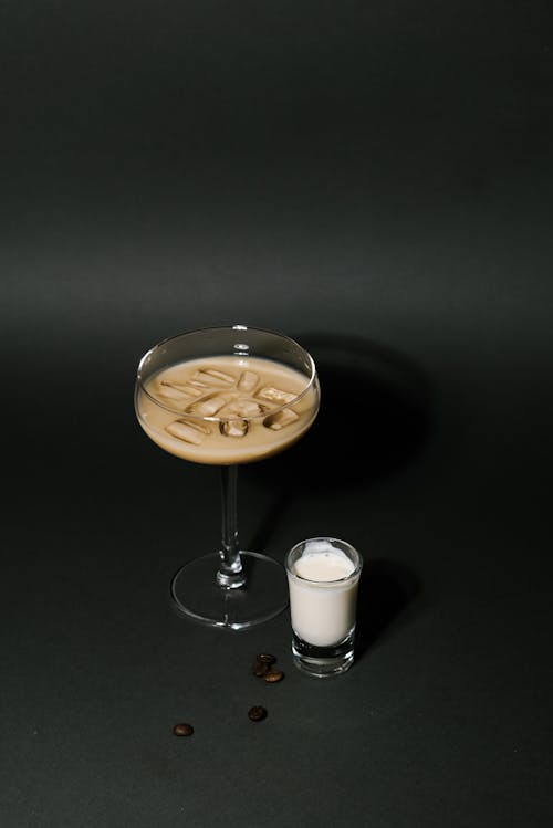 A Glass of Iced Coffee Beside Glass of Milk on a Black Surface