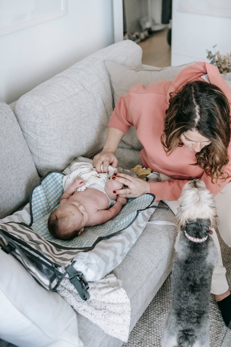 Mother Dressing Baby Near Dog