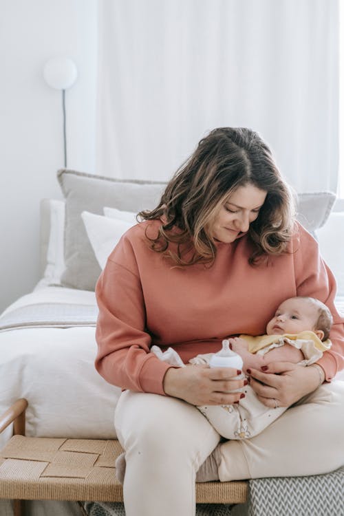 Content mother feeding baby on bed