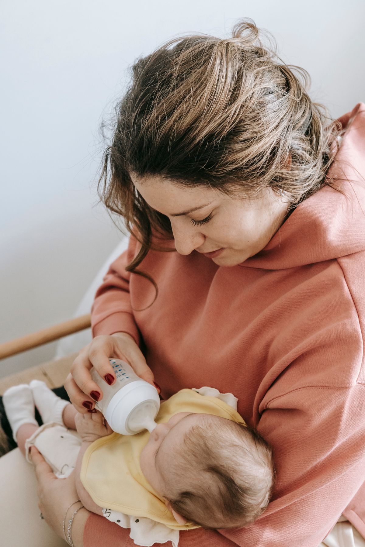 Mother gently bottle feeding her newborn baby in a comfortable home setting