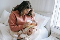 Mother feeding newborn baby on bed