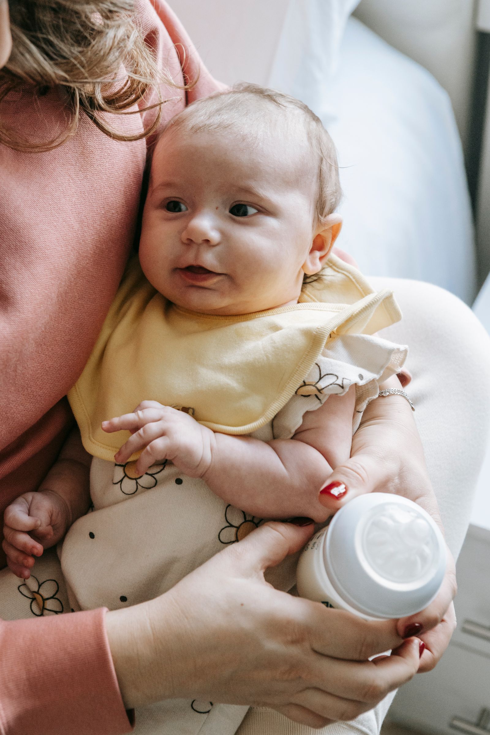 Parent holding and bottle-feeding a baby during a calm family care routine at home