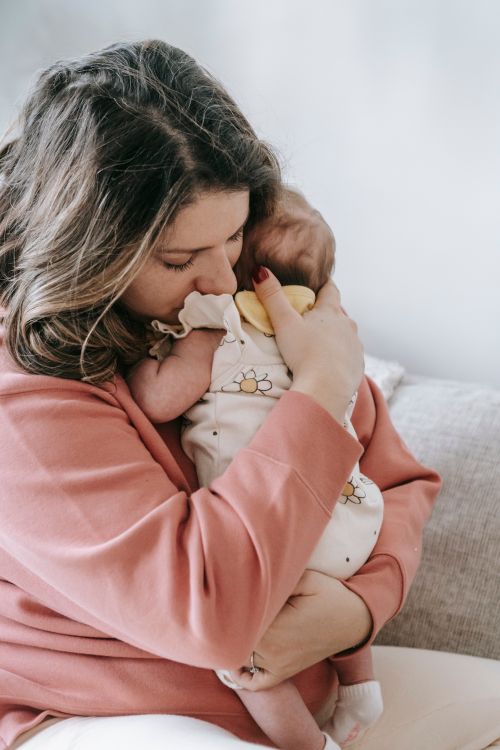 Free A mother tenderly holds her newborn baby, capturing a heartfelt moment of affection and care. Stock Photo