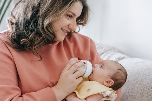 Positive woman feeding newborn baby