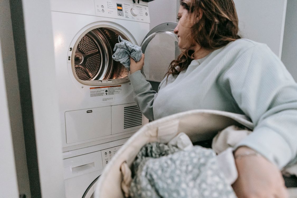Mulher agachada colocando roupas em uma máquina de abertura frontal