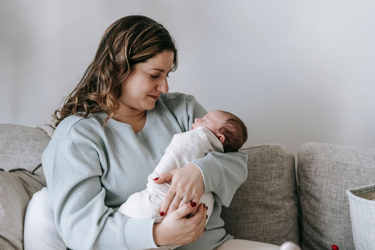 Maman qui berce son nouveau-né dans un salon lumineux et cocooning