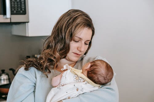 Mother with newborn baby in kitchen