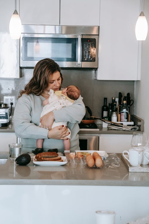 Woman with infant baby near kitchen counter
