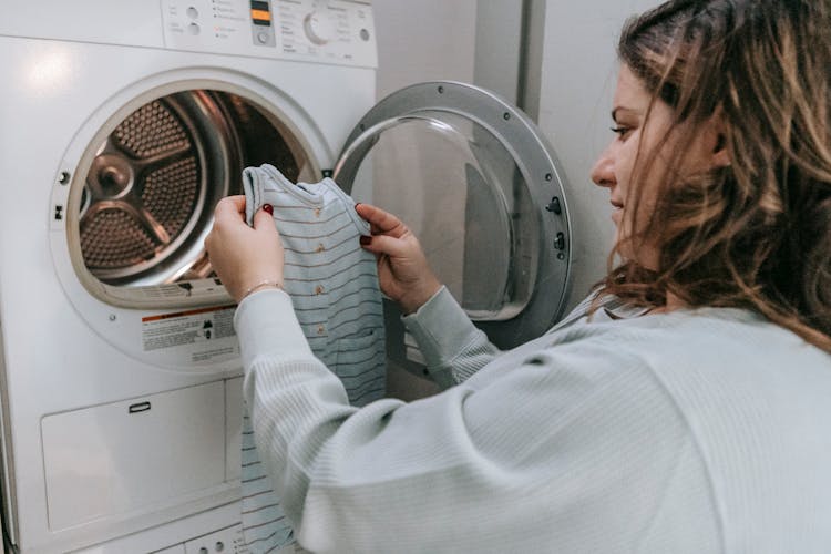 Happy Mother Washing Baby Clothes In Machine