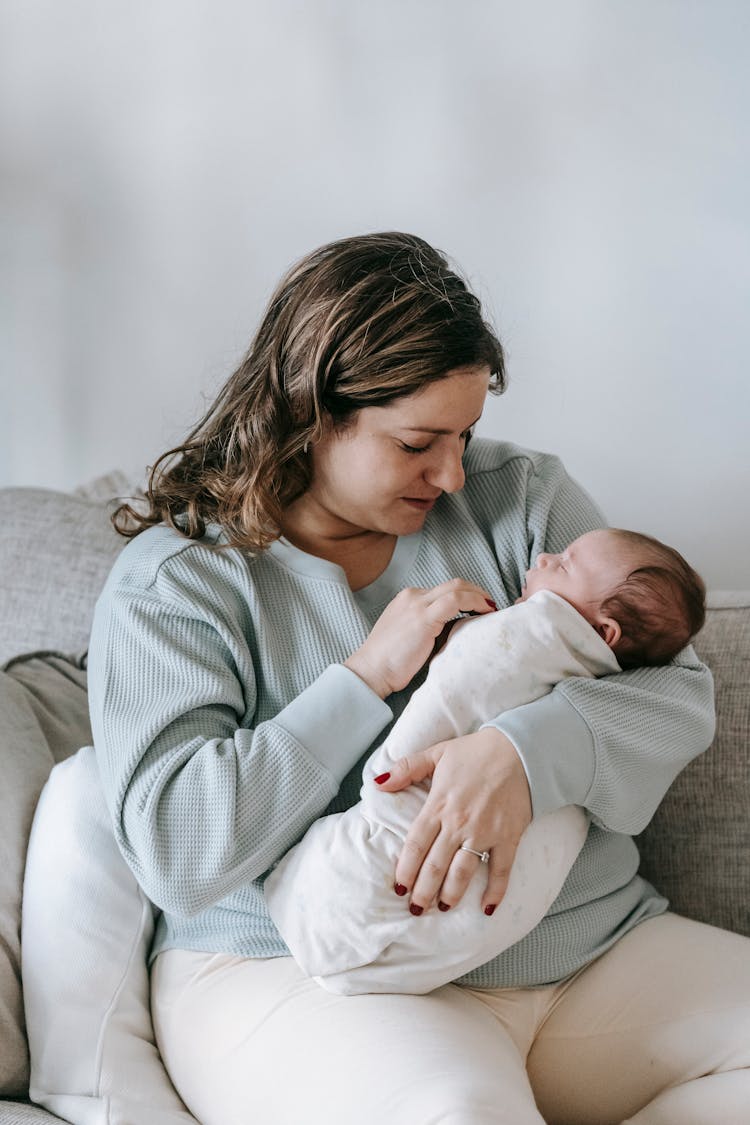 Peaceful Mom Hugging Sleeping Newborn On Sofa