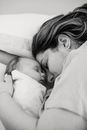 Peaceful young mother with baby embracing and sleeping on bed