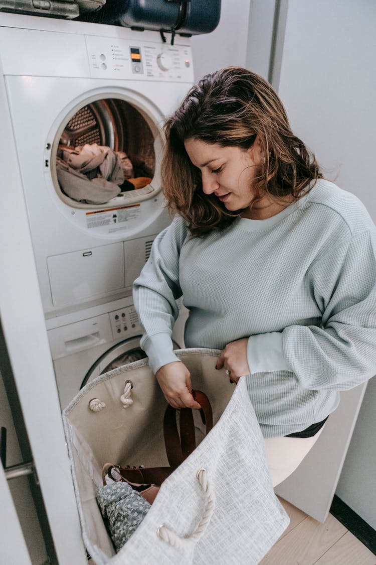 Woman Loading Dirty Clothes Into Washing Machine