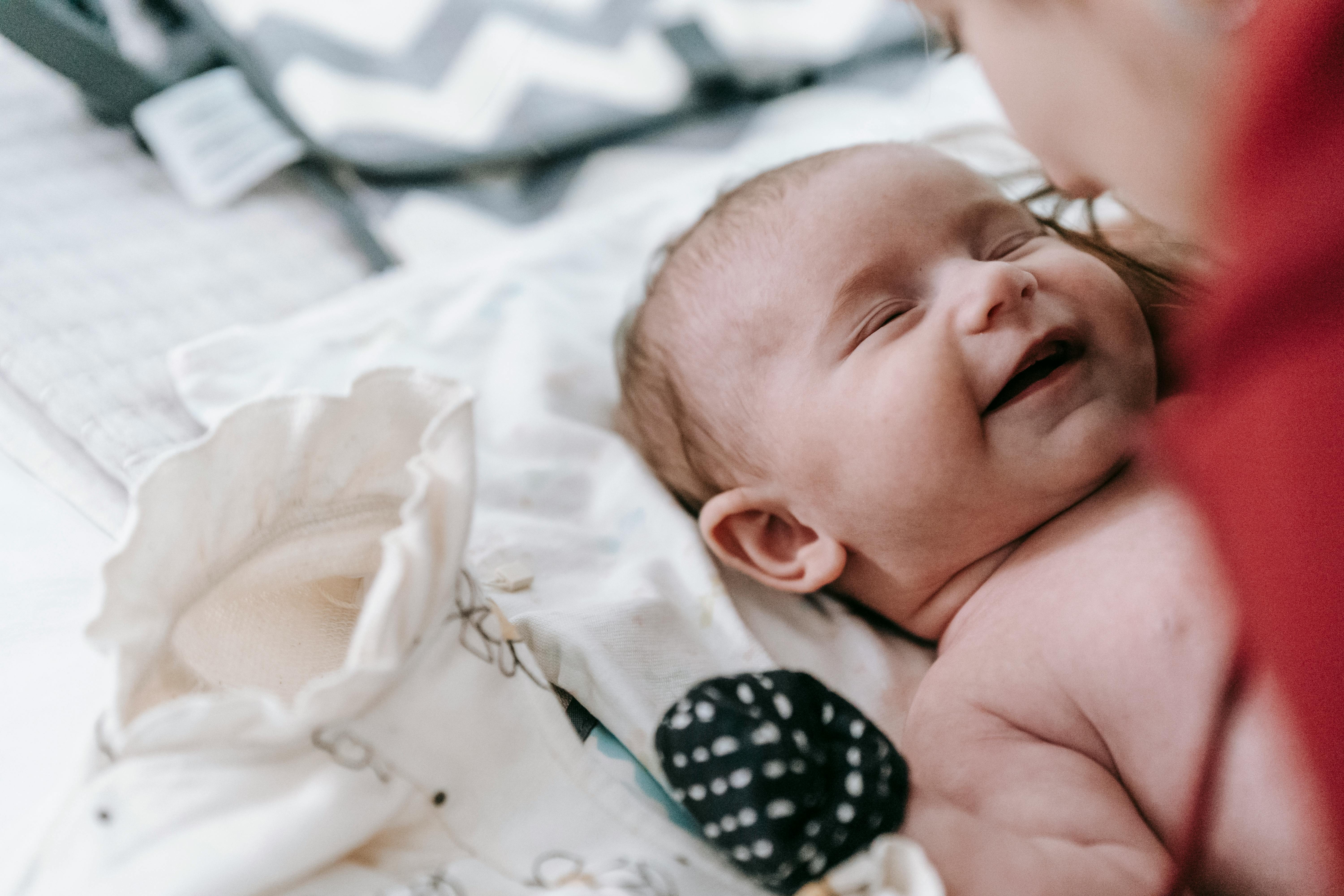 anonymous mom caressing gently smiling cute baby lying on bed