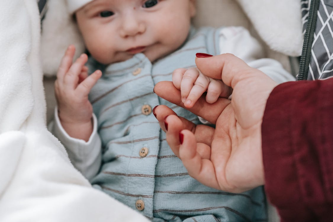 Free Cute newborn holding hand of unrecognizable mom Stock Photo