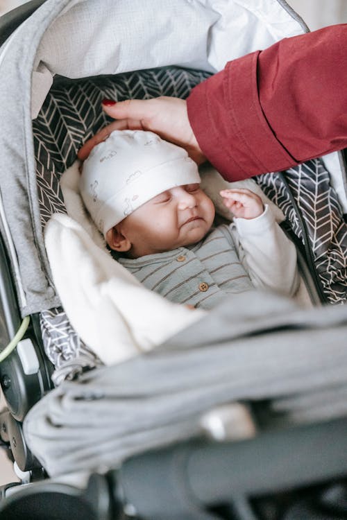 Crop mom caressing baby sleeping in stroller