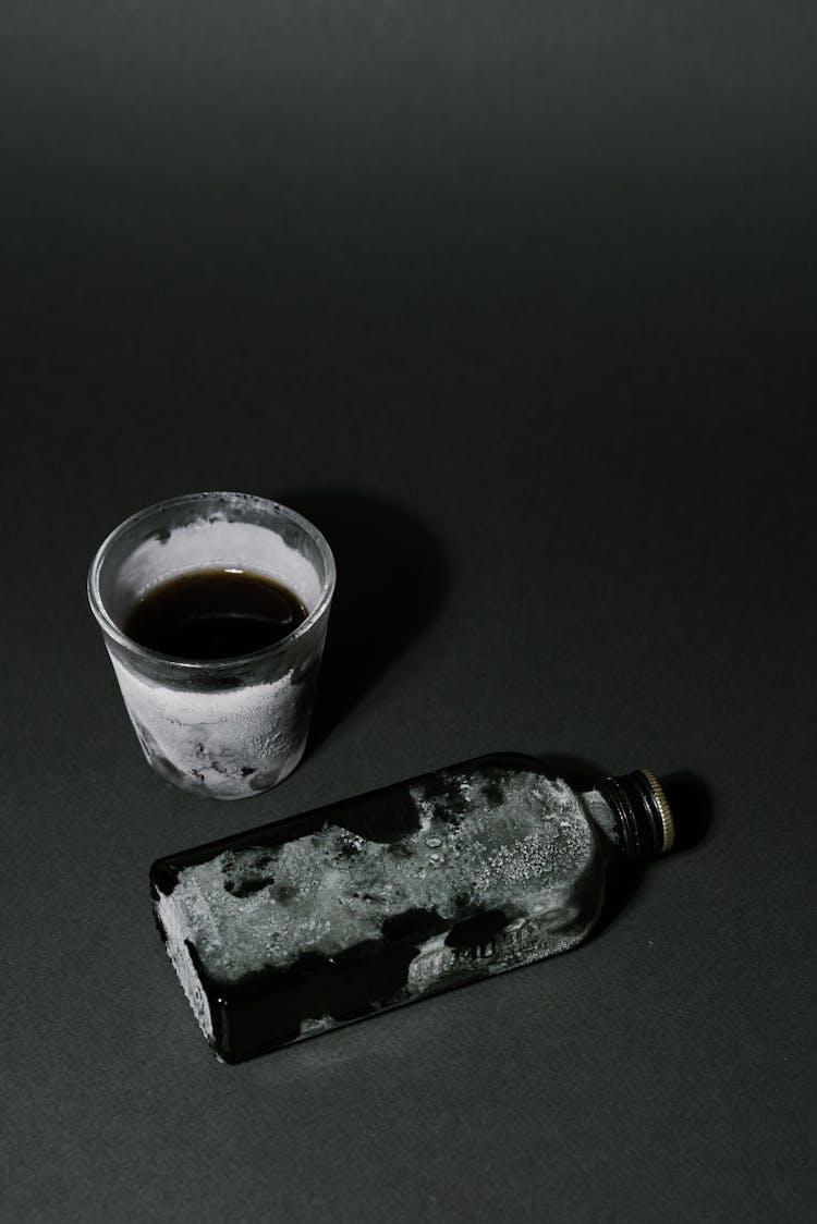 Frozen Glass And Bottle On Black Surface