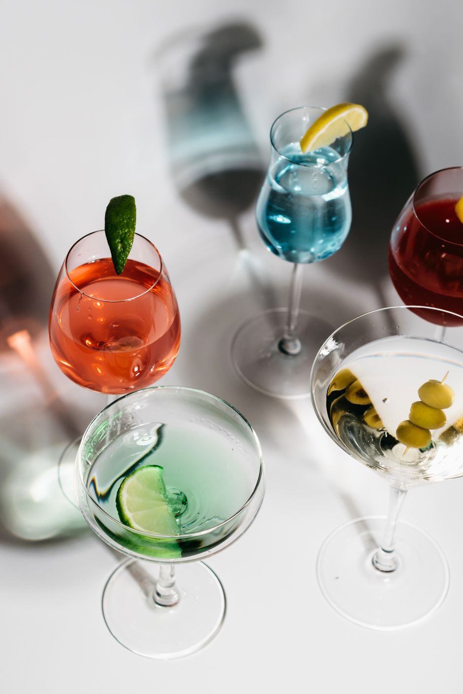 A variety of vibrant cocktails with garnishes on a white background.