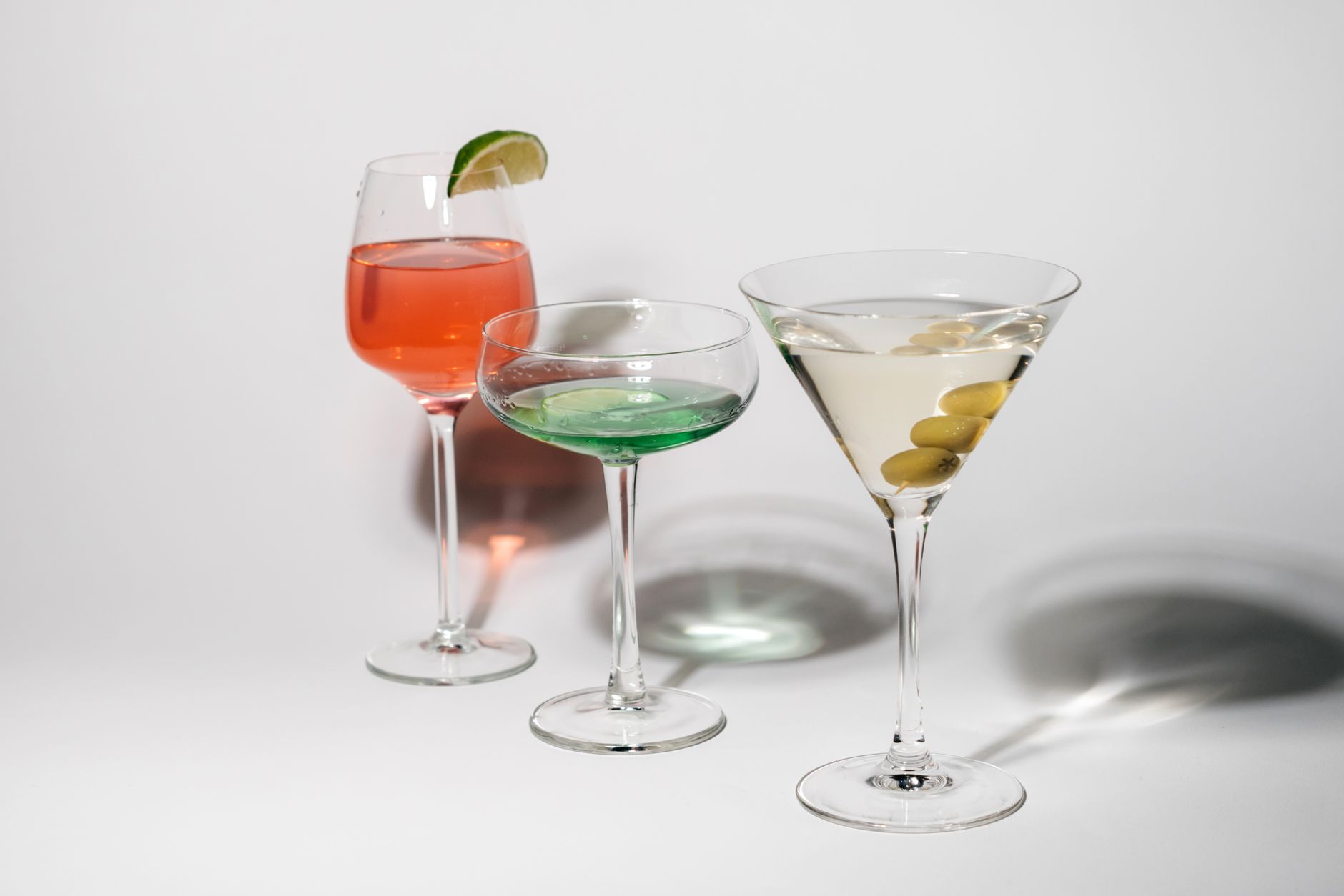 Assorted cocktail glasses arranged on a wooden bar counter with soft lighting