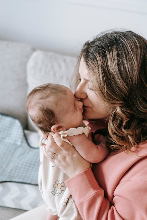 Happy mother kissing cute baby on couch