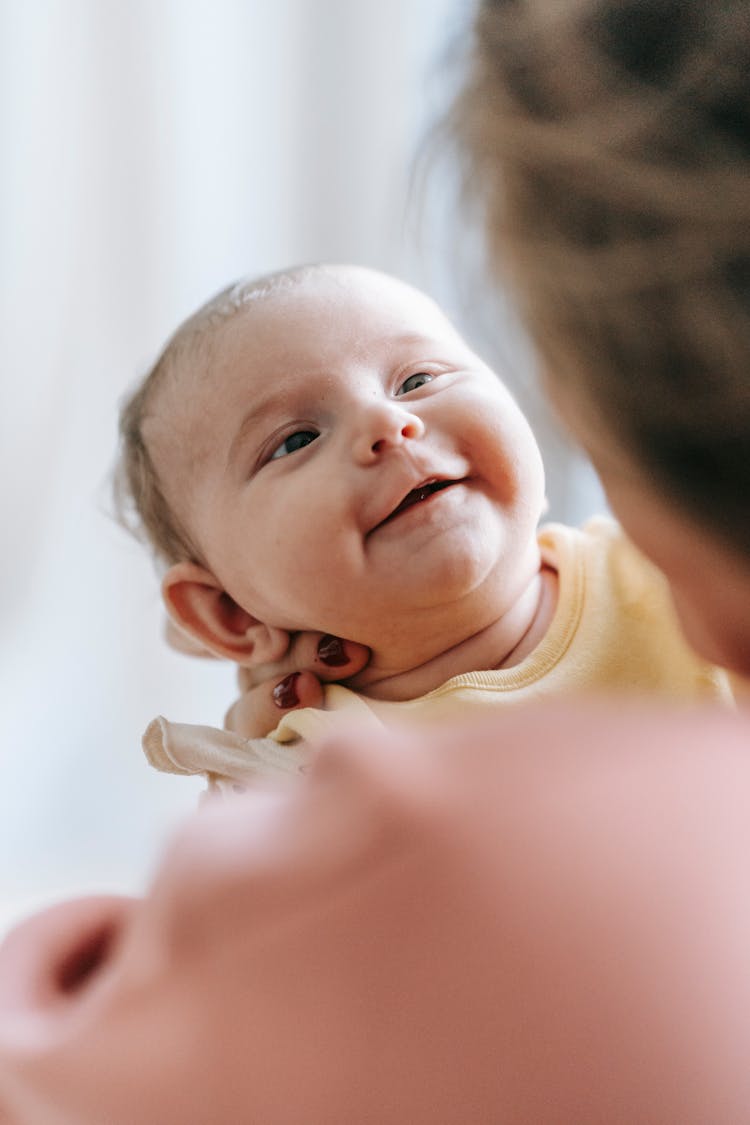 Happy Newborn Smiling And Looking At Mom