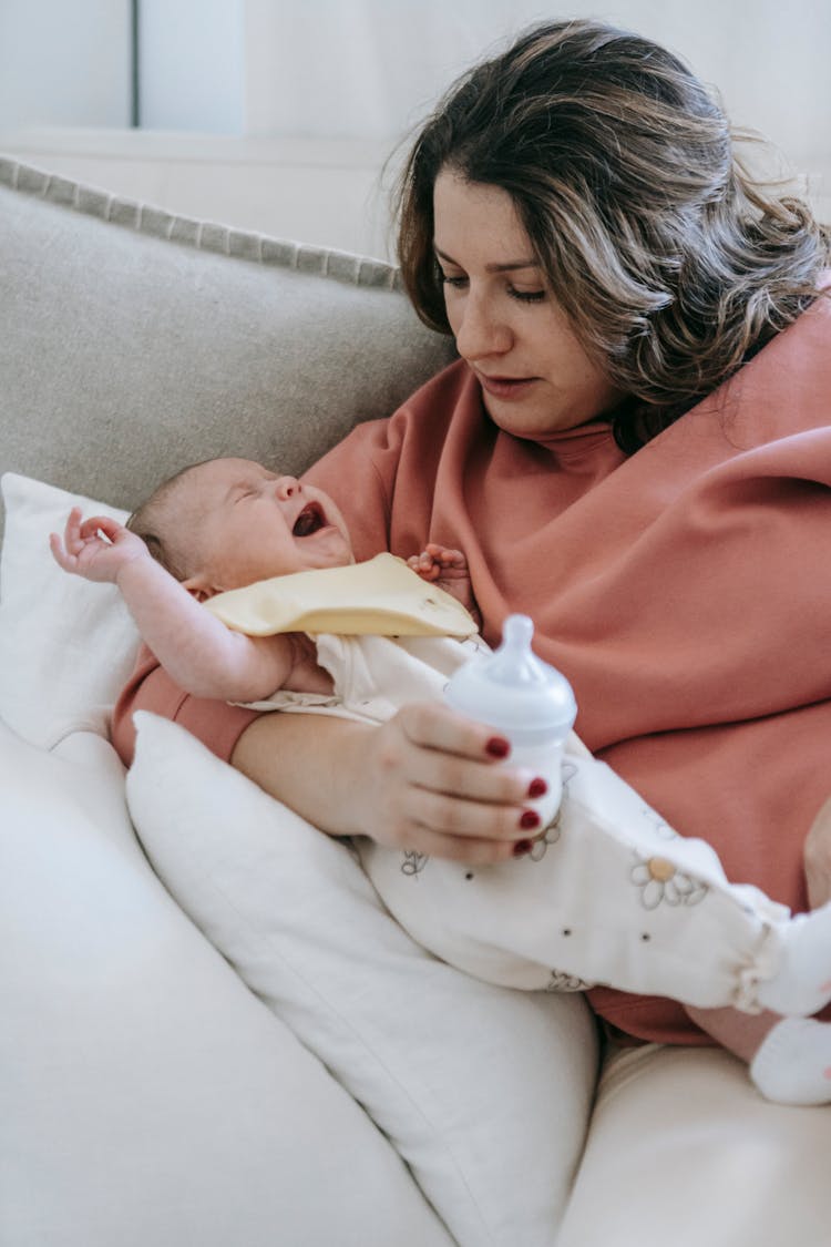 Newborn Crying Loudly In Hands Of Young Mother