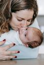 Smiling mother kissing cute infant with closed eyes