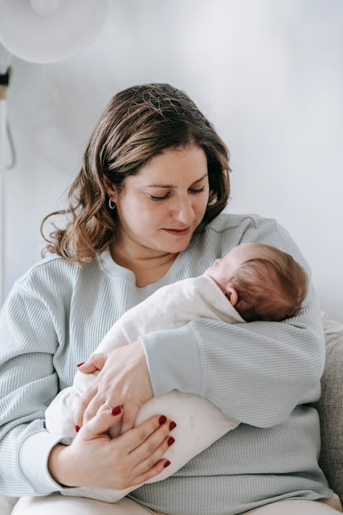 Peaceful mom hugging newborn on couch