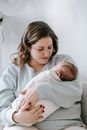 Peaceful mom hugging newborn on couch