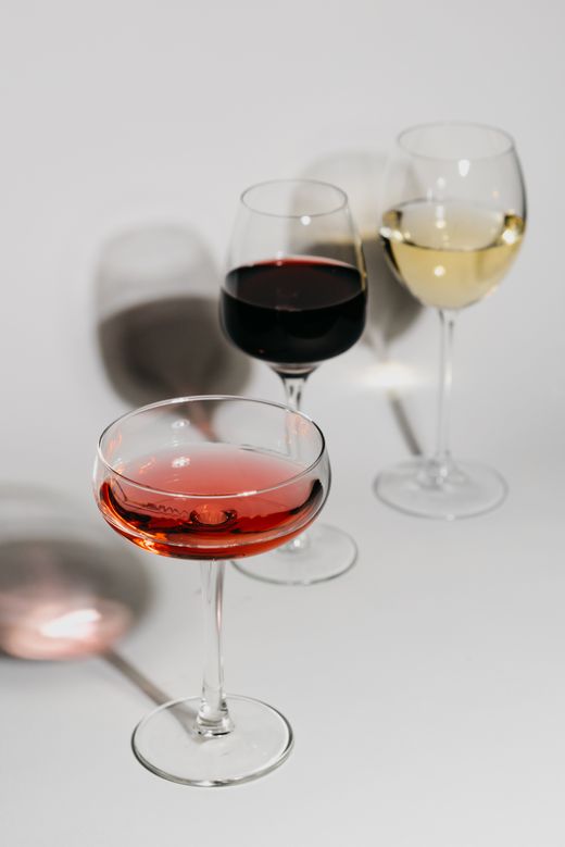 Coupe of rose, red wine glass and white wine glass on white